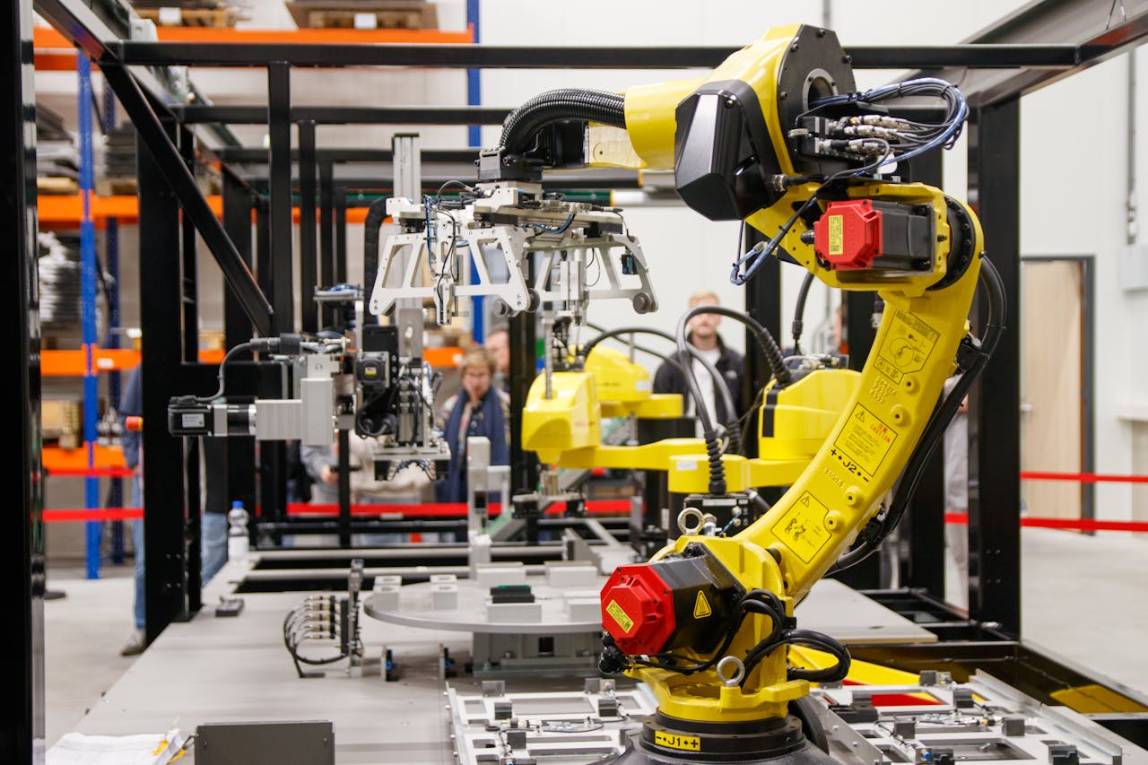 services-04 Close-up of a yellow industrial robotic arm in action at a modern manufacturing facility.